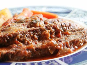 A Swiss steak resting on a blue and white plate 