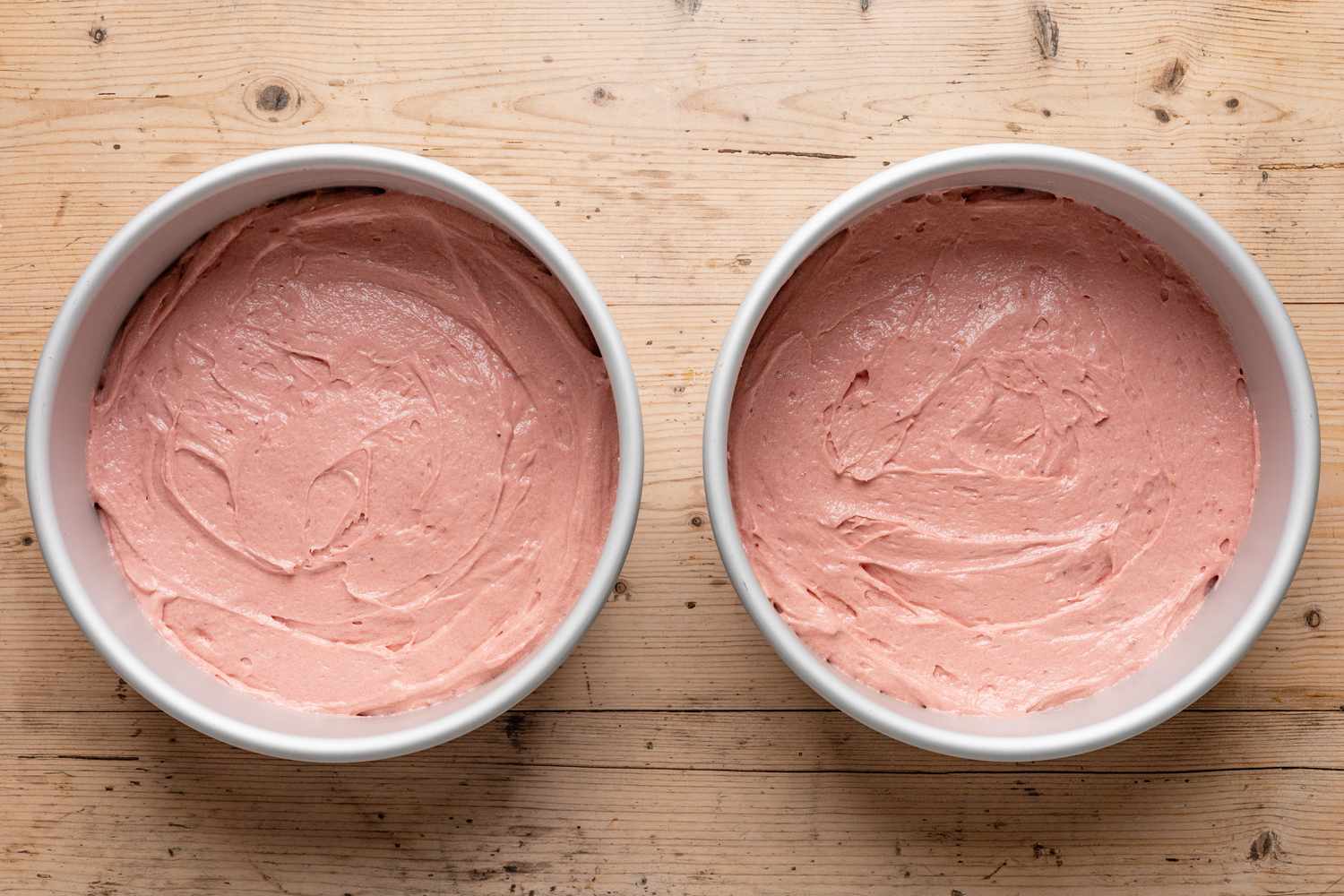 strawberry cake batter added to the lined round baking pans 