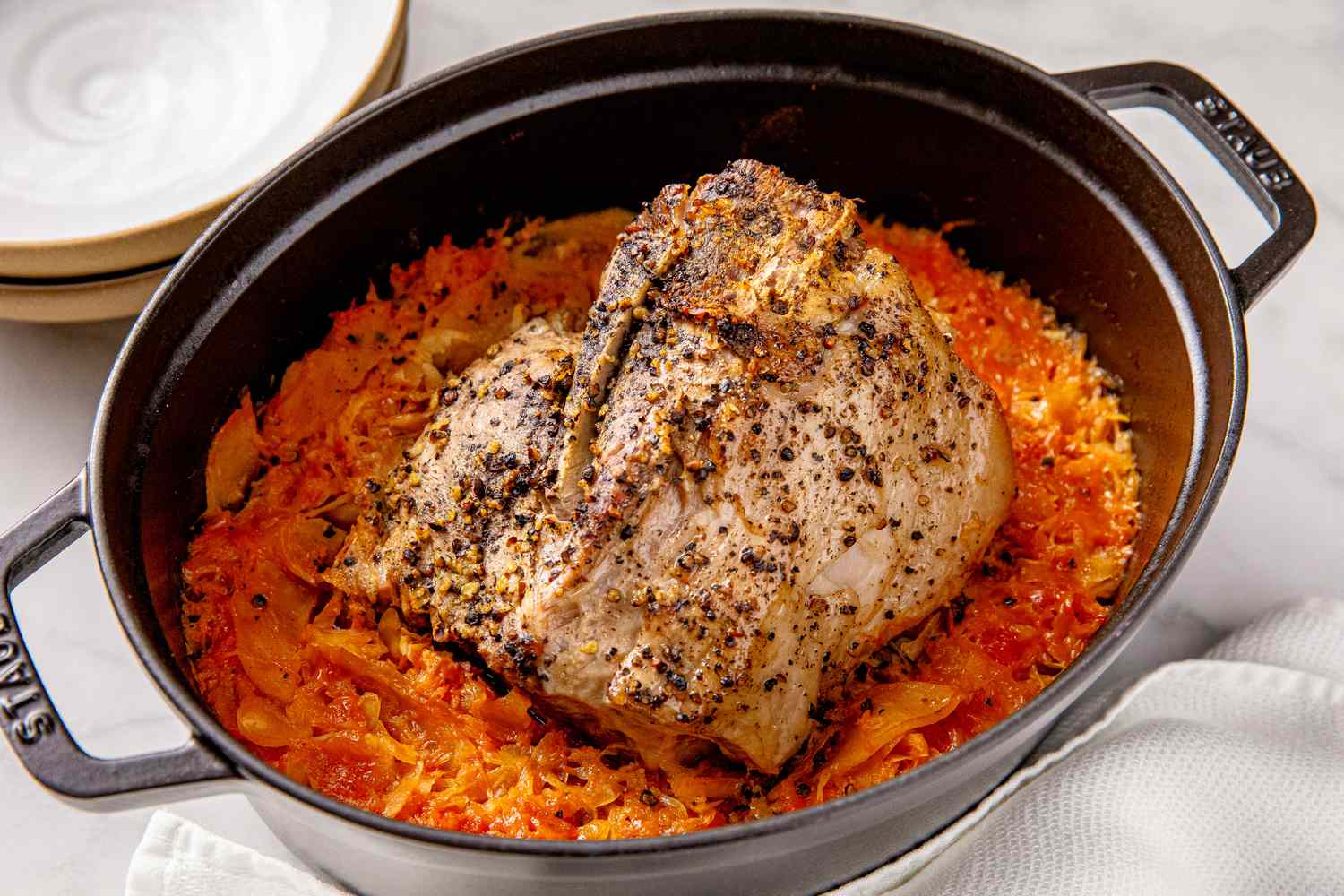 Braised pork roast on a bed of sauerkraut in a black Dutch oven