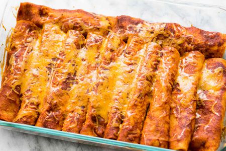 Easy Chicken Enchiladas in pan covered in red chili sauce and cheese