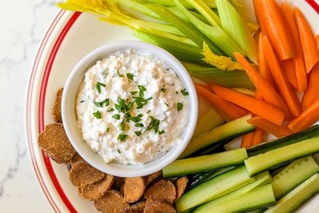 Spiced Cottage Cheese Dip in a bowl with veggies/melba toast around it