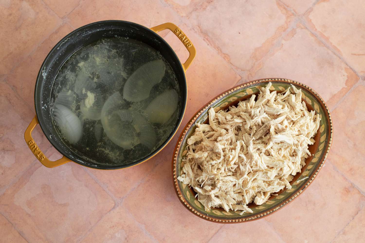 Platter of Shredded Chicken Next to a Cast Iron Pot with Chicken Stock for Chicken Tamales Recipe