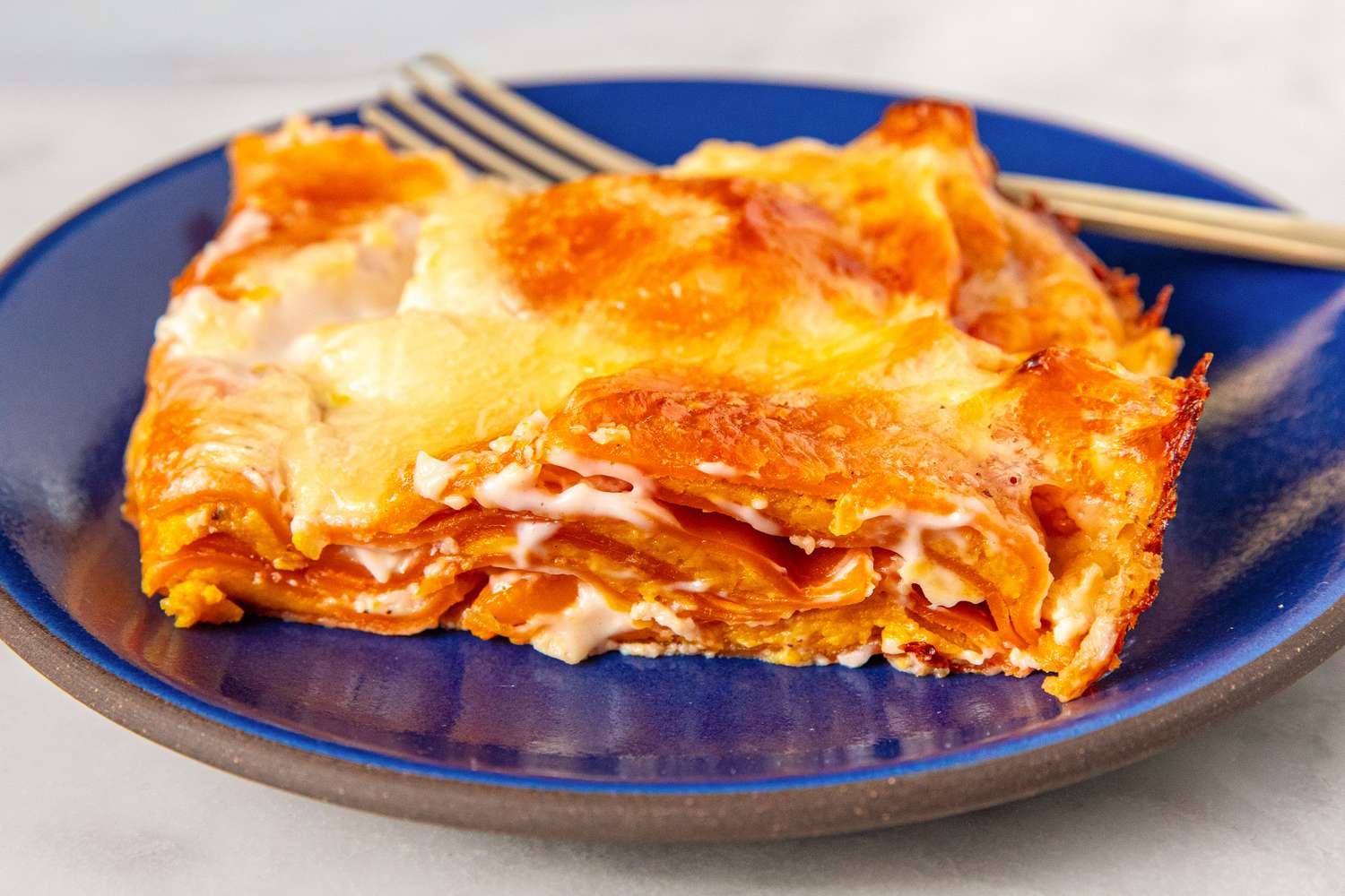 A serving of lasagna on a blue plate