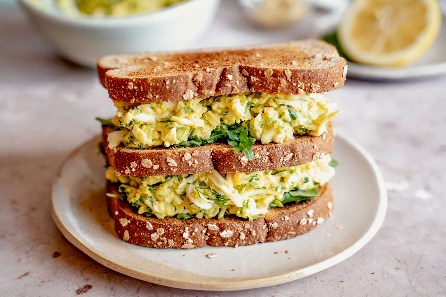 Side view of a triple decker sandwich made from mayo-free egg salad on a small plate