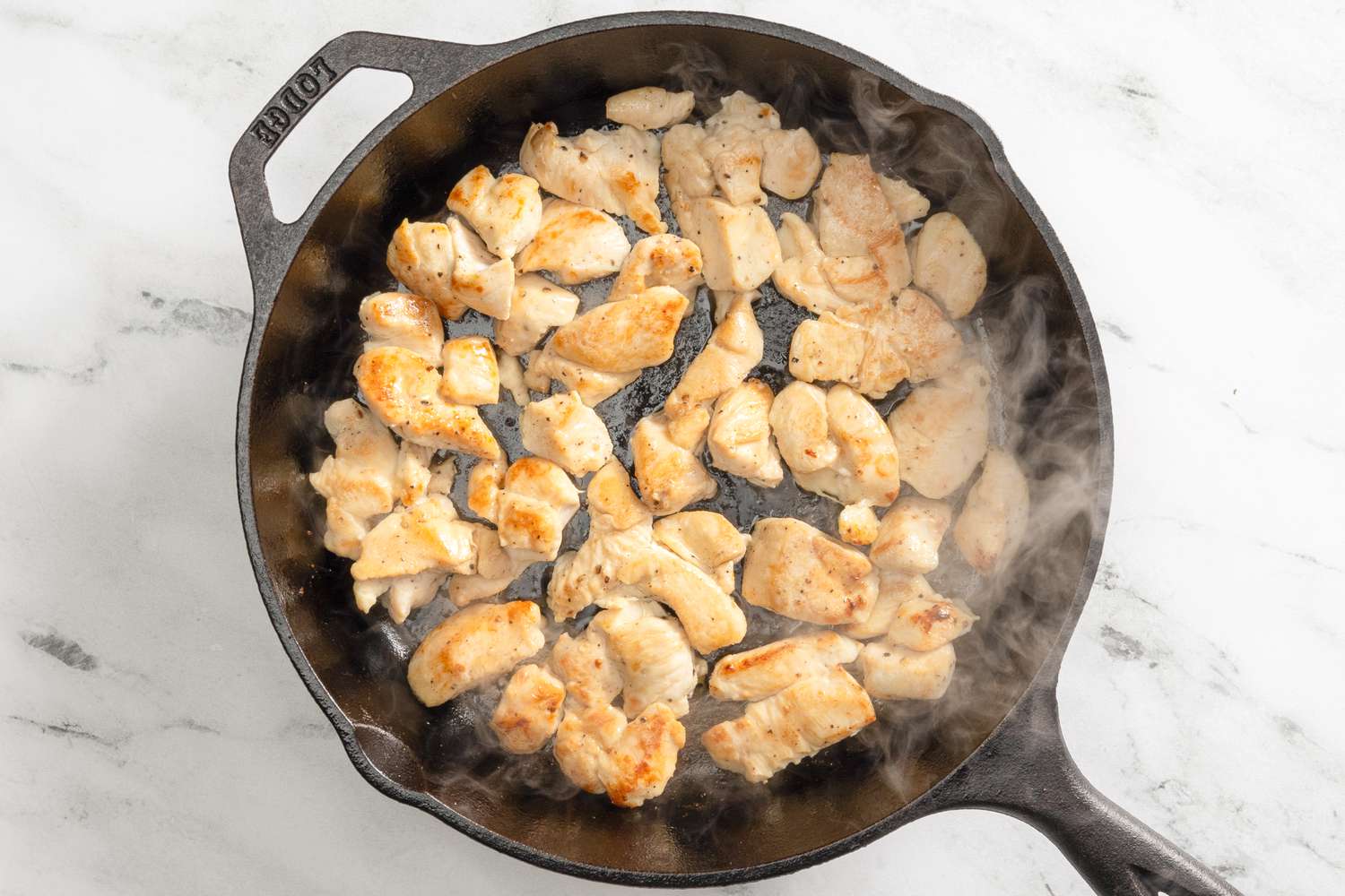 chicken cooking in a cast iron skillet for chicken divan recipe