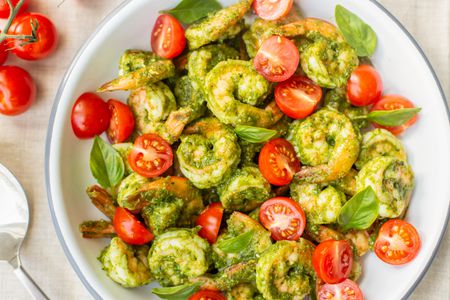 5-Ingredient Pesto Shrimp with Cherry Tomatoes in a Bowl Next to Cherry Tomatoes on a Vine