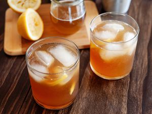 Two Gold rush cocktails with ice on a wood background.