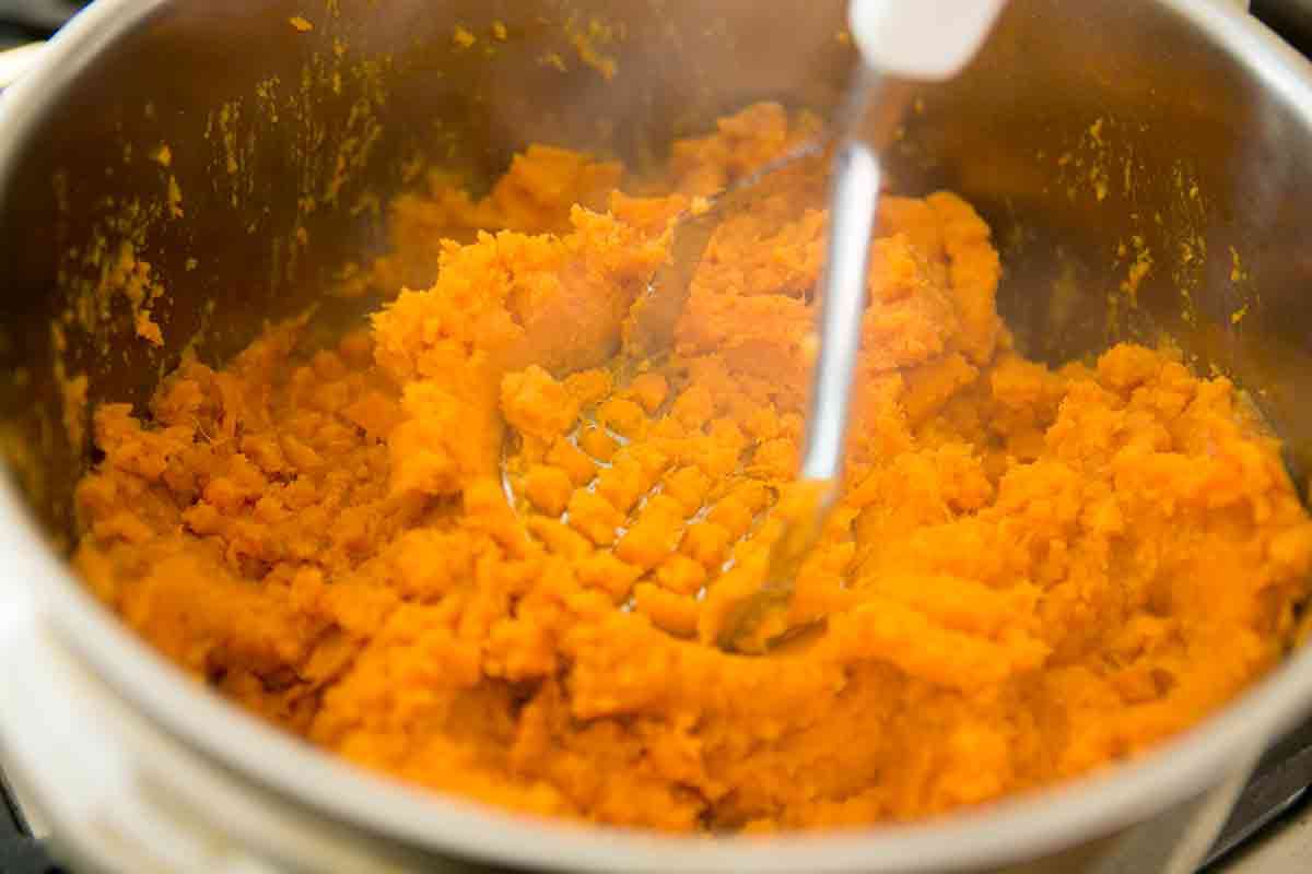 sweet potatoes being mashed in a pot