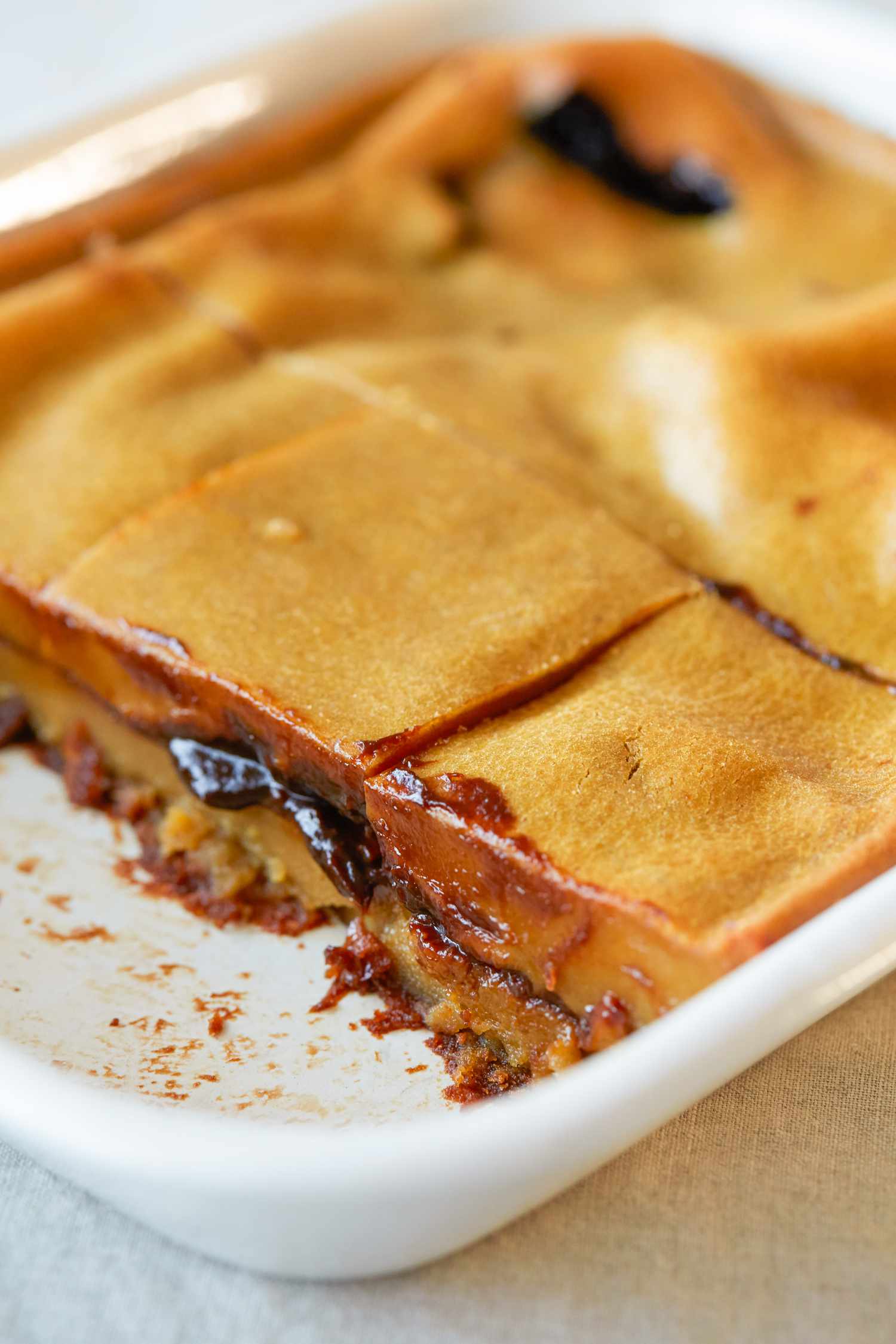 Sticky rice cake with red bean paste in a baking dish with a few slices missing.