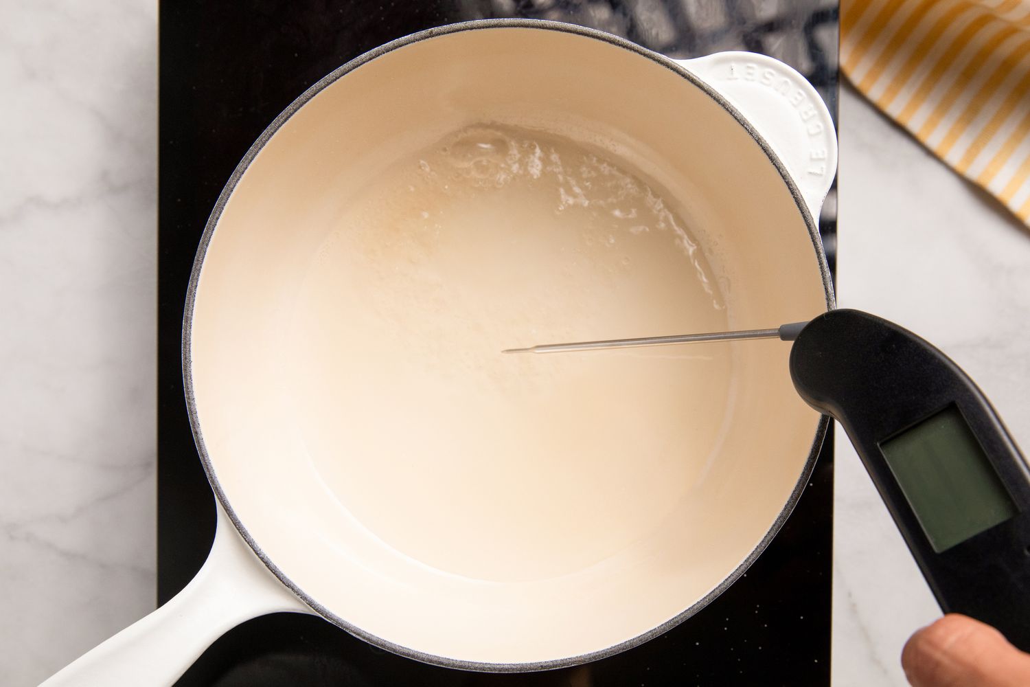 overhead view of pot of sugar and water with hand measuring temperature with a thermometer for Southern Banana Pudding