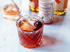 Vieux carre in a whiskey glass with ingredients to make the cocktail behind it.