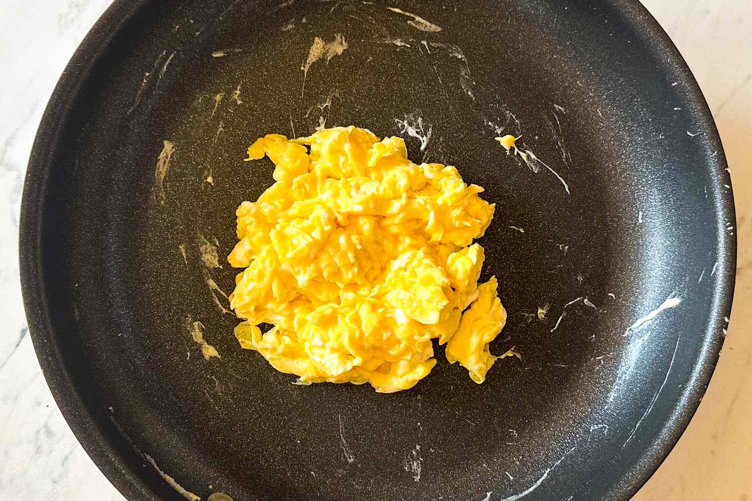 Scrambled eggs served in a black frying pan