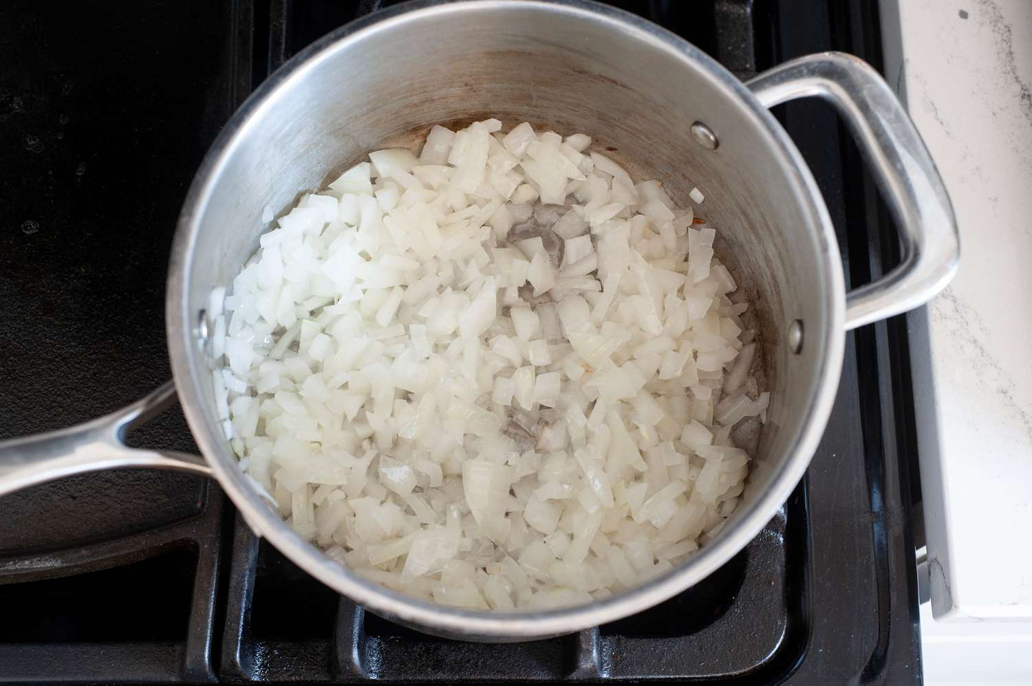 Onions cooking in a pot to make Turkish-style braised green beans.