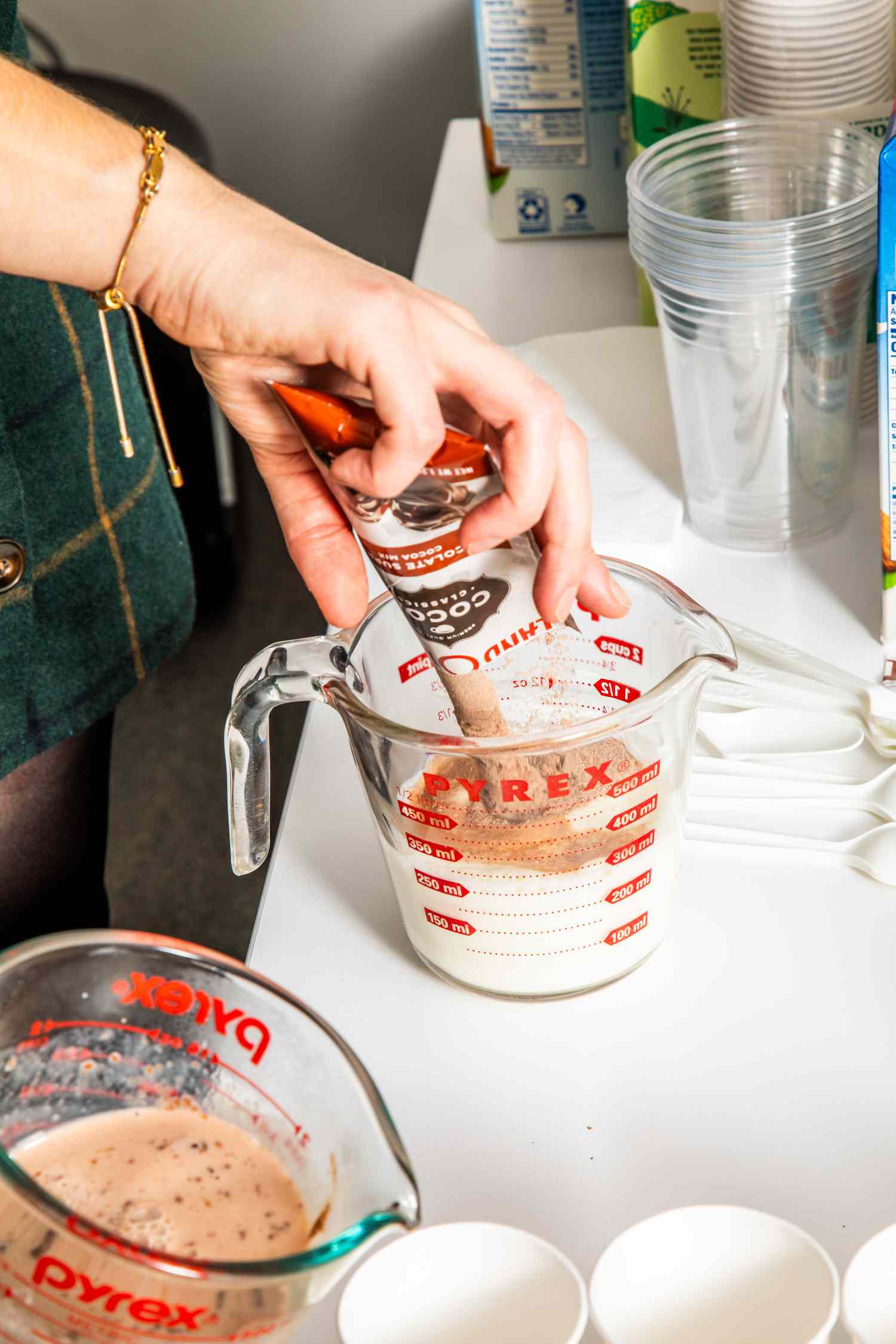 Hand pouring hot cocoa mix into a measuring cup