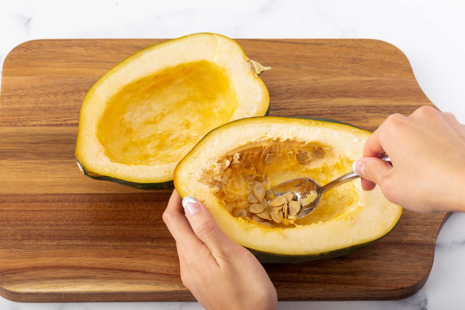 Spooning the seeds out of an acorn squash.