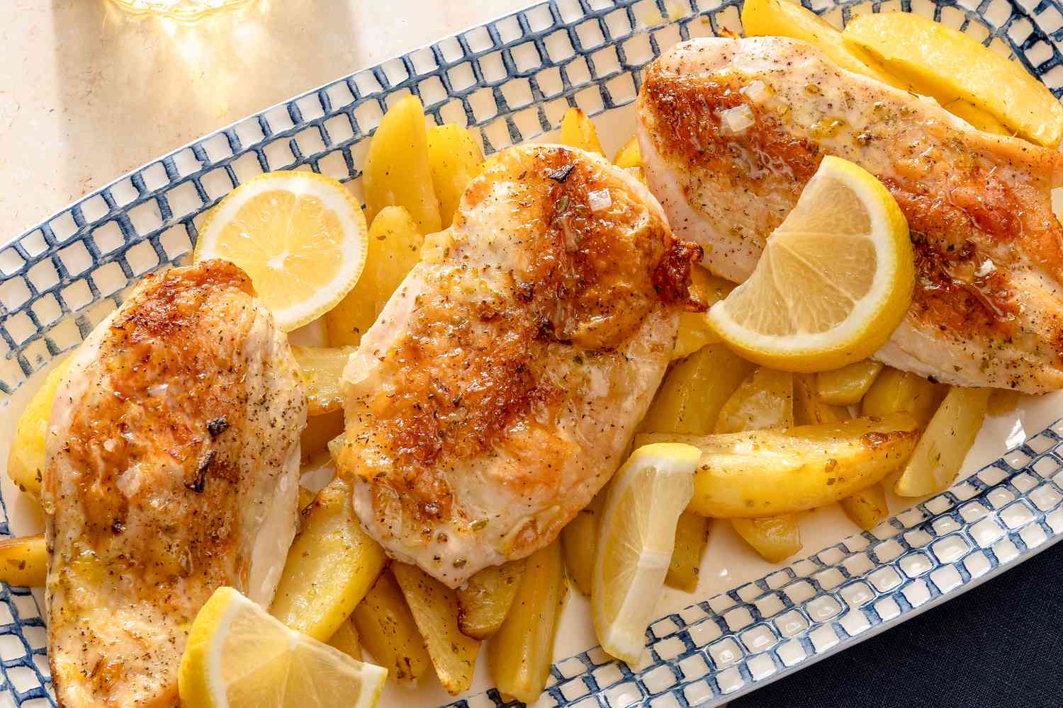 Greek-Style Lemon Chicken and Potatoes on a platter garnished with lemon slices
