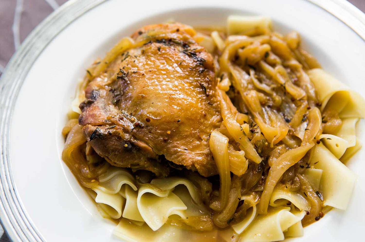 A plate of braised onions and chicken thighs on pasta