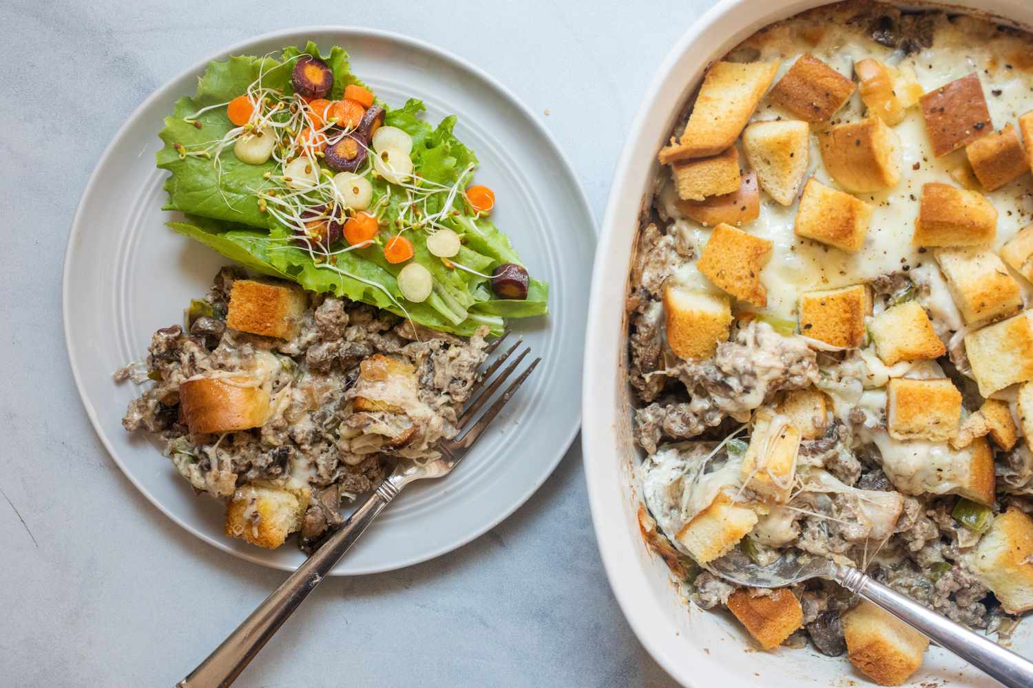 Philly cheesesteak casserole on plate with side salad.