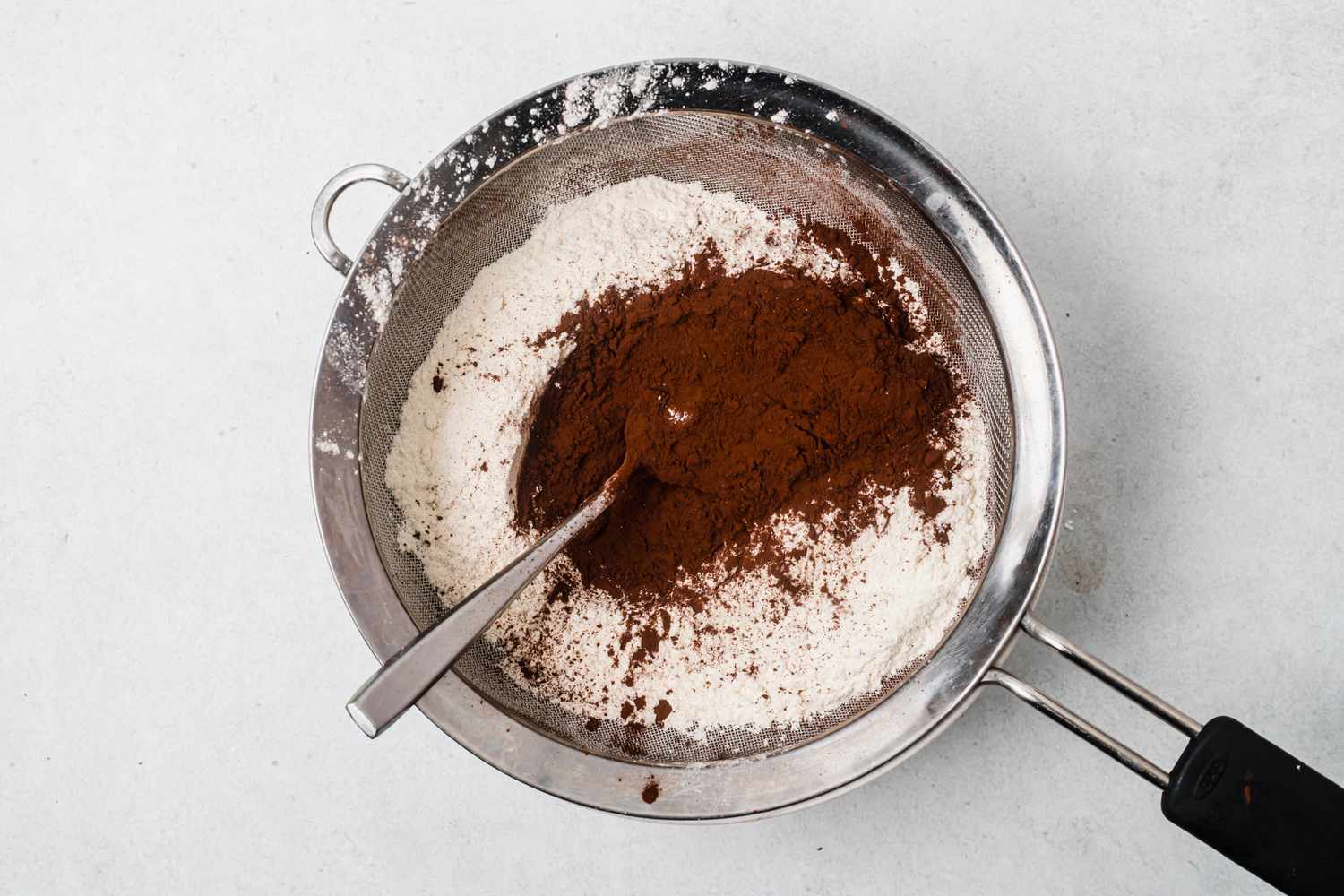 Sifting dry ingredients to make shortbread dipped in chocolate and peppermint.