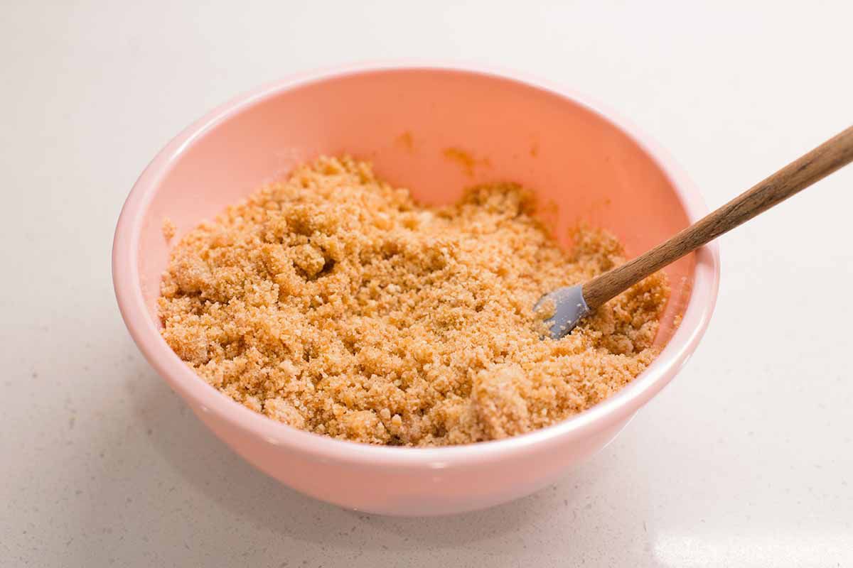 Crushed vanilla waffers in a pink bowl with a spatula.