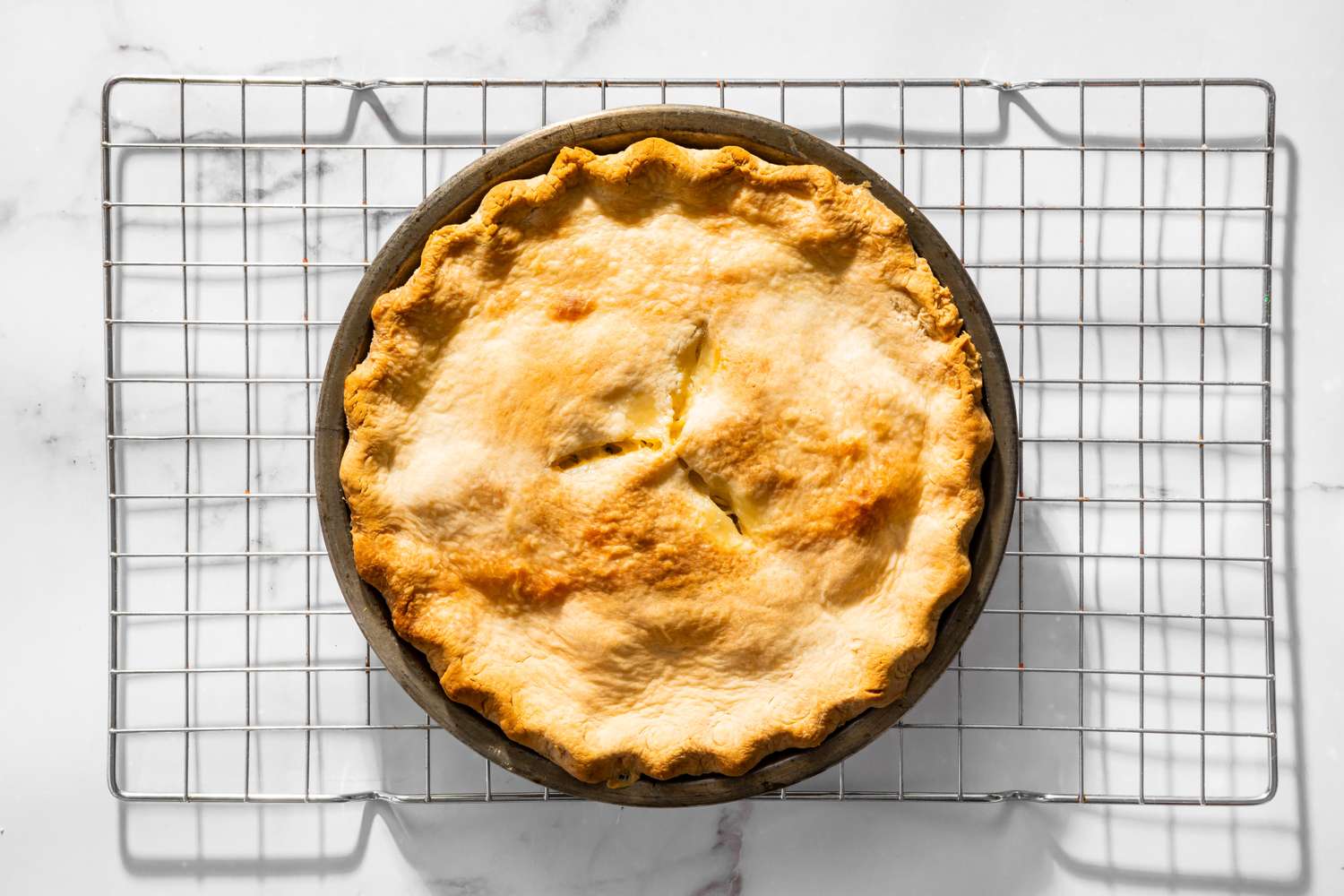 Overhead view of a baked chicken pie on a cooling rack for Moravian Chicken Pie recipe
