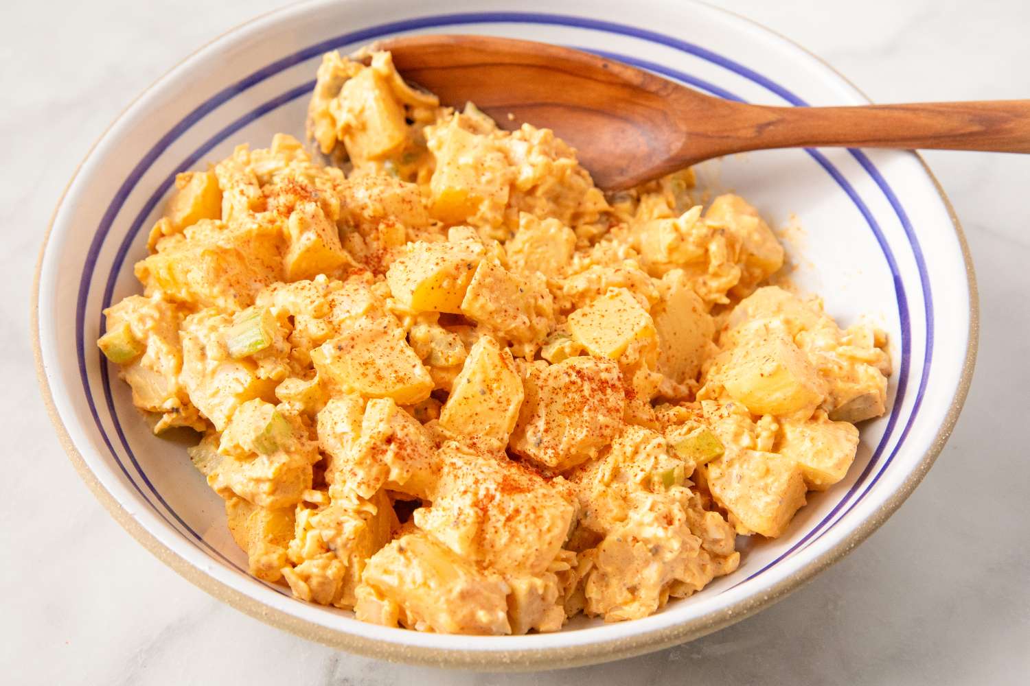Deviled Egg Potato Salad in a bowl with a wooden spoon