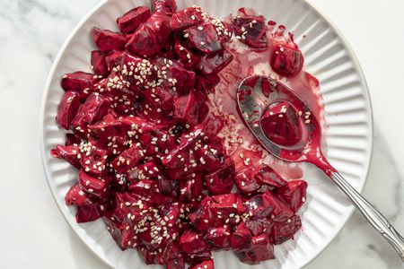 Overhead shot of a plate with chopped pieces of beets in a creamy sauce, topped with sesame seeds