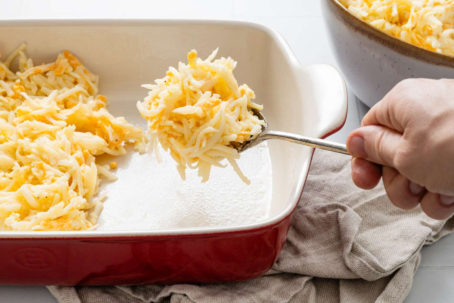 Copycat Cracker Barrel hash brown casserole mixture spooned into a casserole dish