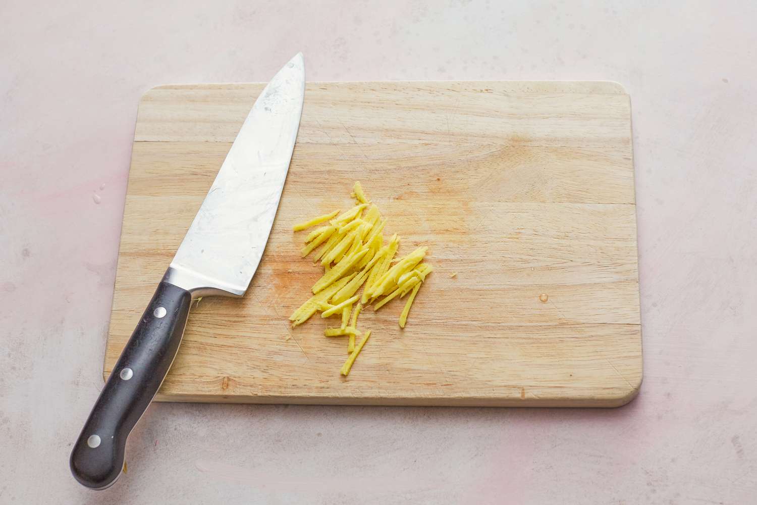 Cutting ginger into matchsticks with a chef's knife to make whole steamed black sea bass
