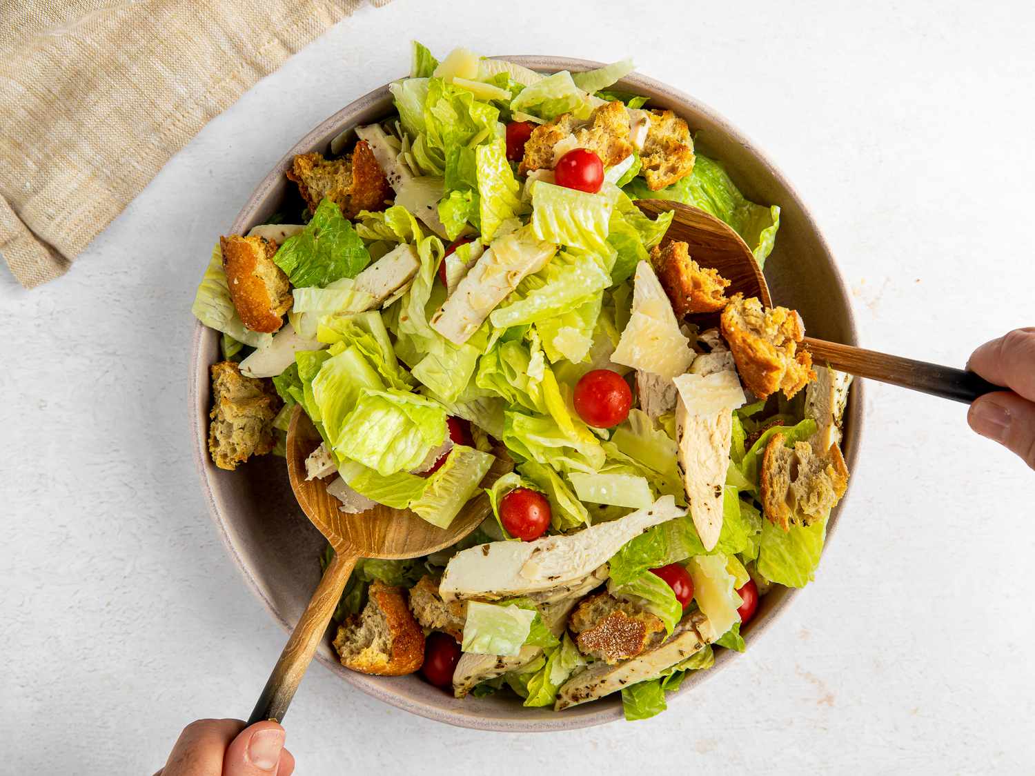 Two salad spoons used to mix sheet pan caesar salad