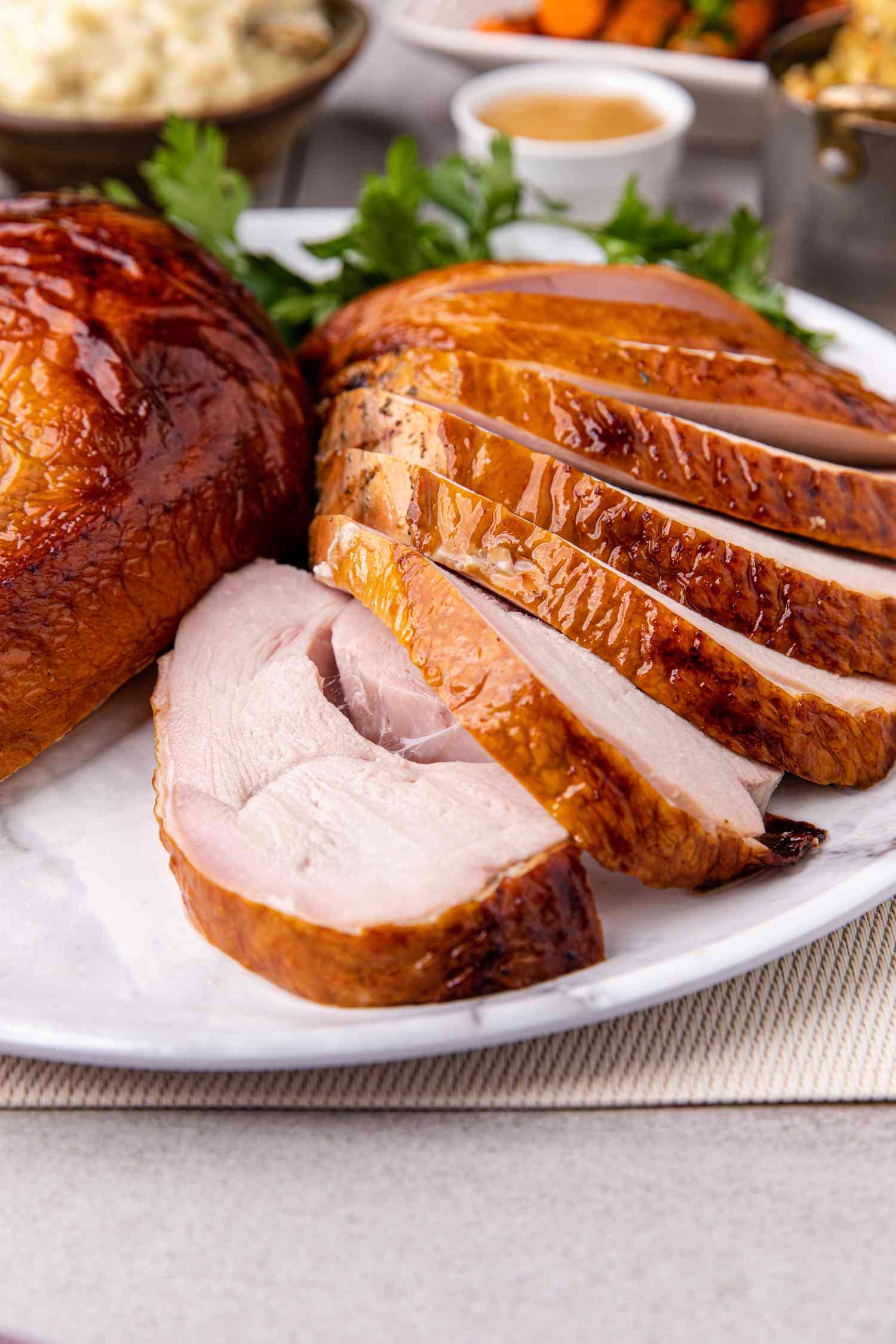 Apple and sage-brined smoked turkey breast sliced on a platter.