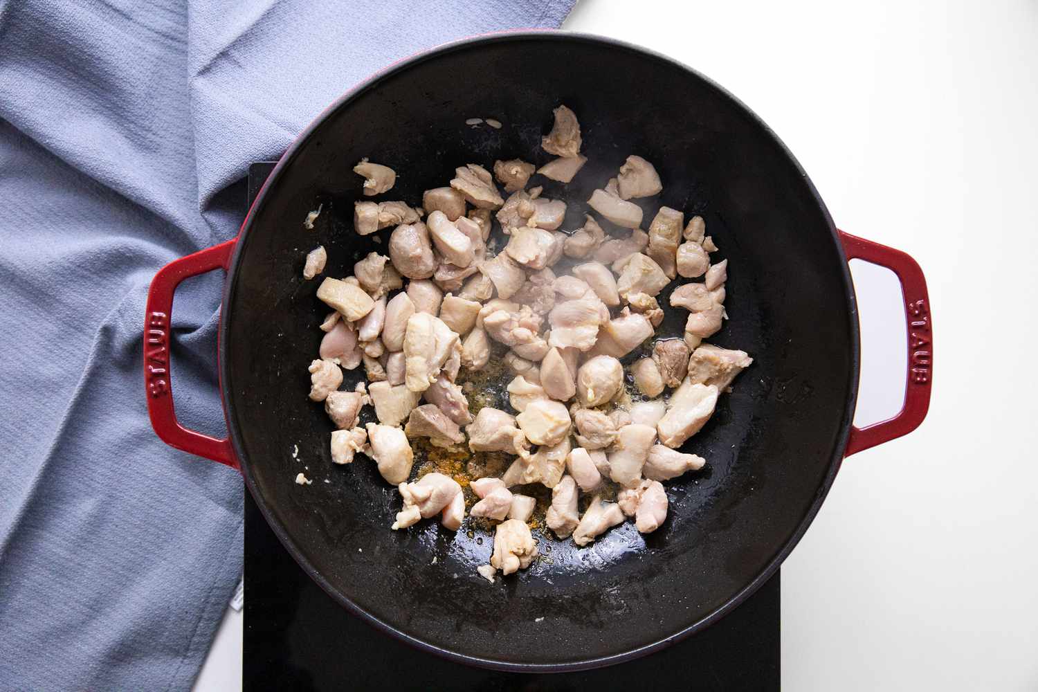 Cooked Chicken in a Wok on a Portable Burner, and Next to It, a Blue Kitchen Towel for Chop Suey Recipe