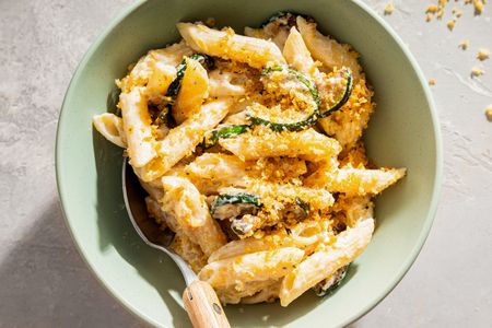 A bowl of penne pasta with ricotta cheese zucchini and breadcrumbs