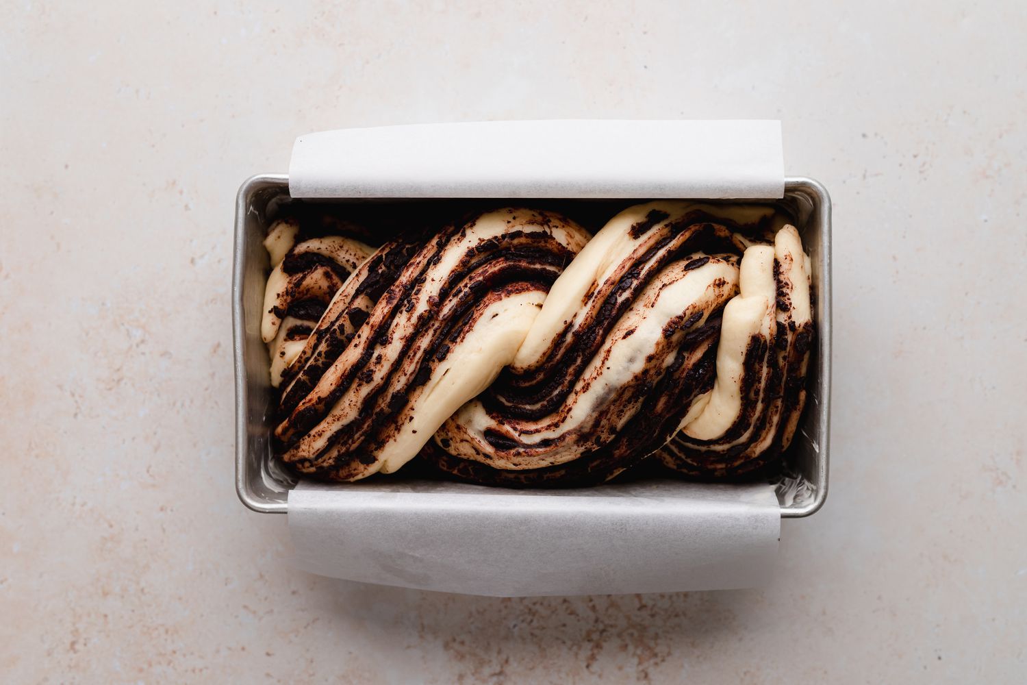 Braided chocolate babka in a loaf pan and ready to be baked.