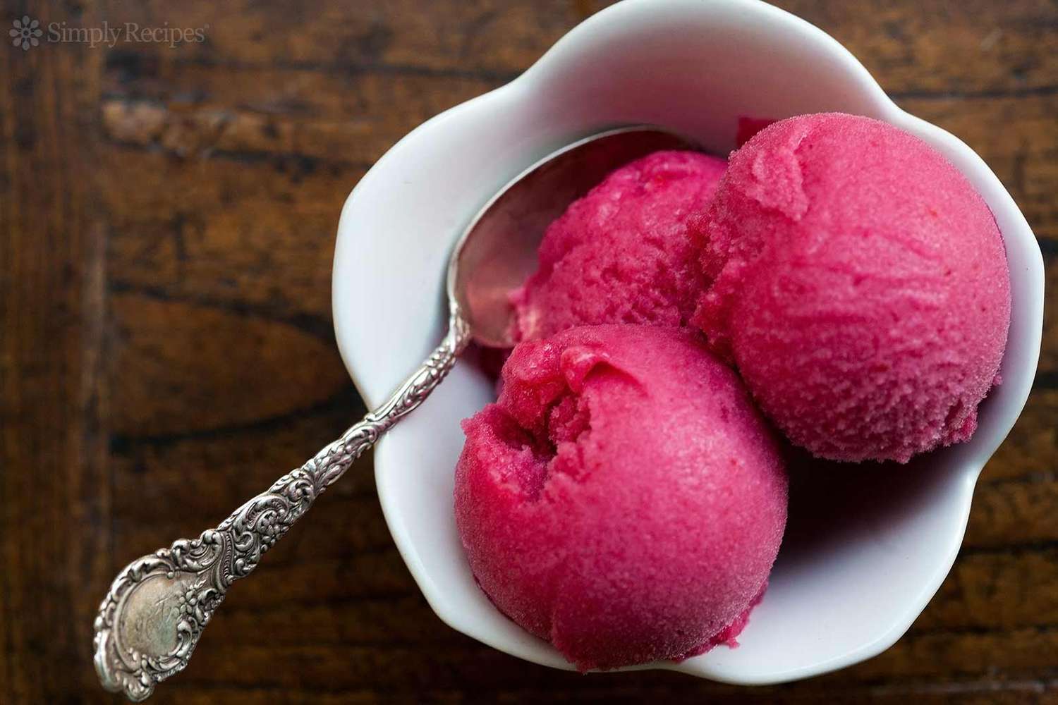 A bowl with three scoops of cranberry sorbet and a spoon