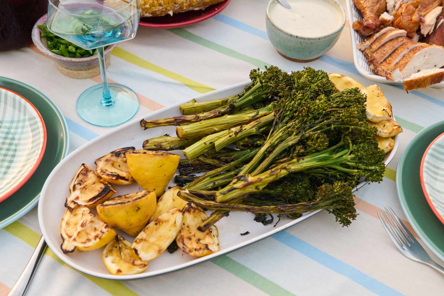 Grilled broccolini and lemon slices on a serving plate on a set table