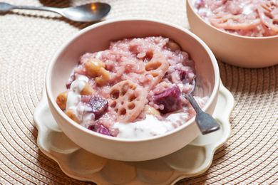 Coconut rice pudding with lotus and sweet potato served in a bowl with a spoon.