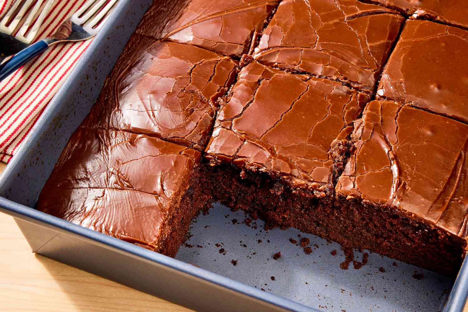 Metal baking pan of sliced coca cola cake with two slices removed