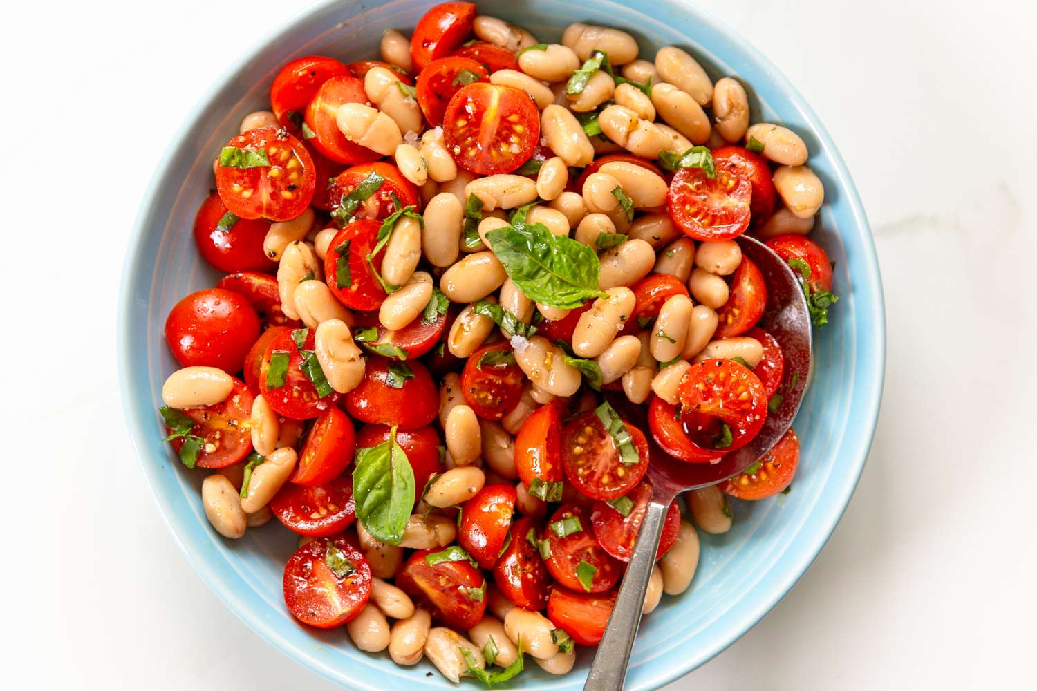 White bean and cherry tomato salad with basil leaves