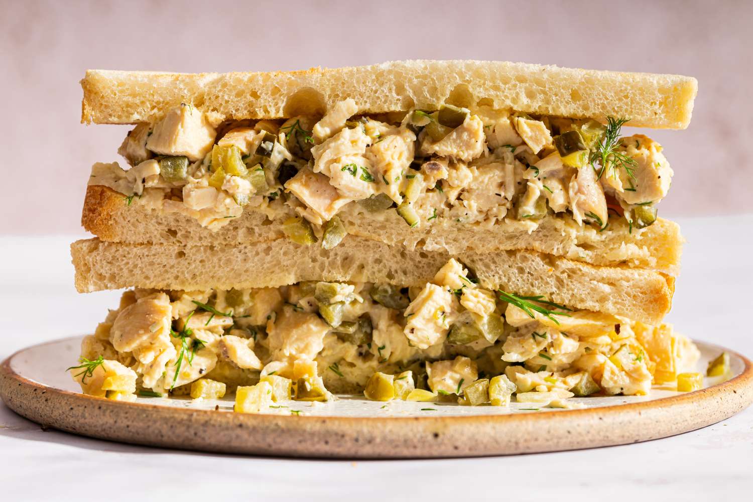 A chicken salad sandwich cut in half displayed on a plate