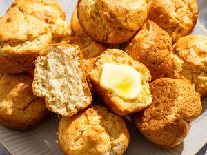 Mayonnaise Muffins on a platter, one muffin on top is cut in half, one side spread with butter
