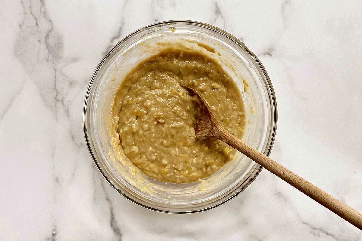 Easy gluten free banana bread batter in a bowl with a wooden spoon.