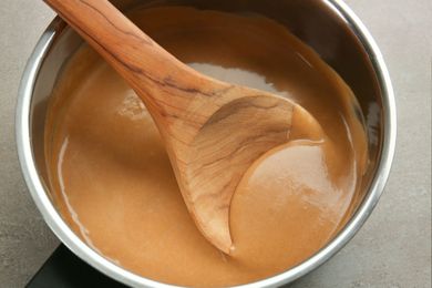 Wooden spoon stirring gravy in a saucepan