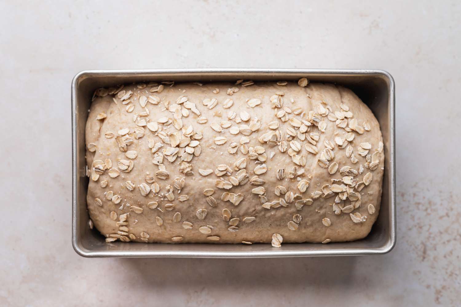 Oat bread loaf rising in a loaf pan.