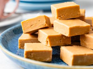 Penuche on a plate, and in the background, a teacup and a stack of plates