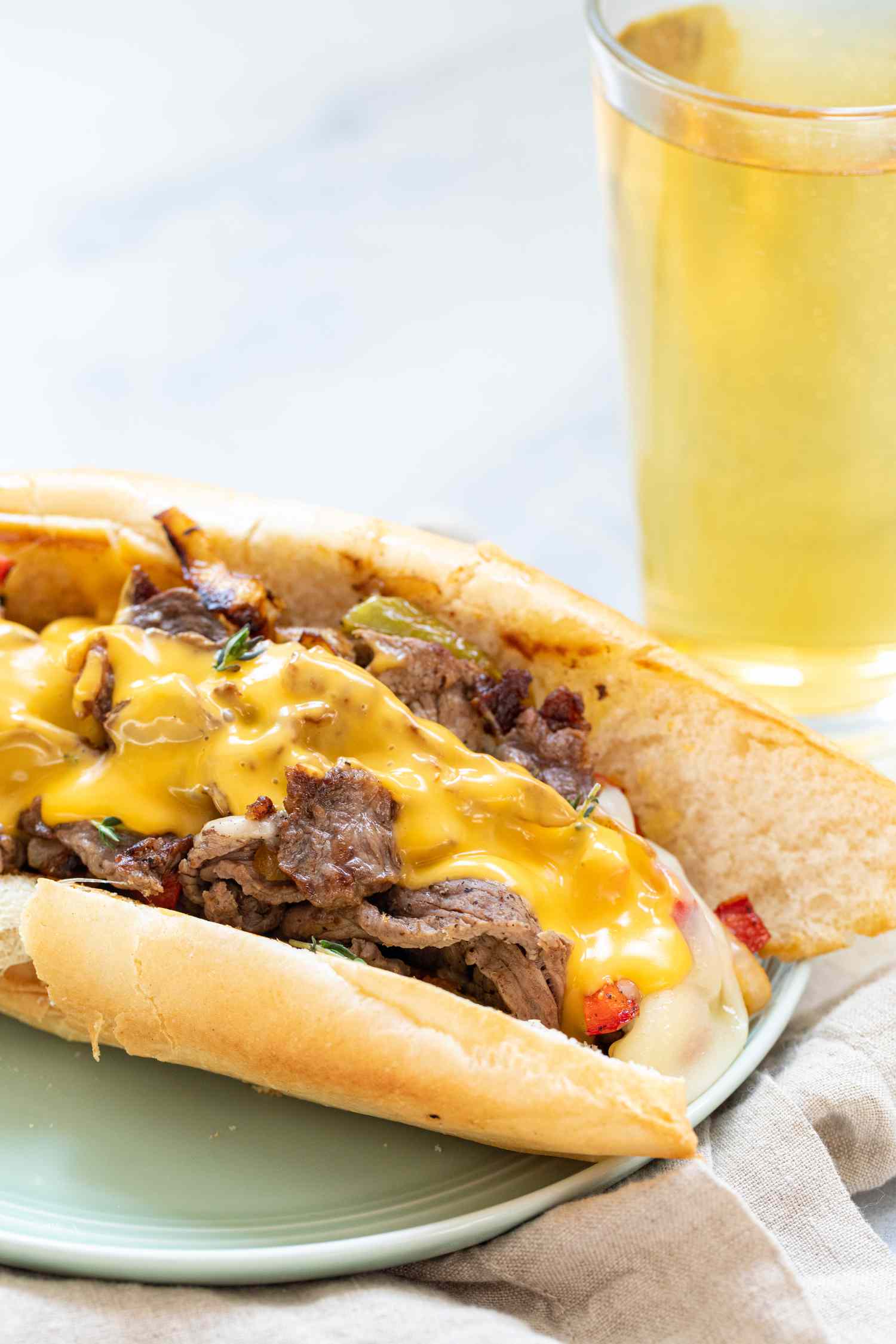 Philly Cheesesteak Sandwich with Onions and Peppers topped with cheese and on a plate.
