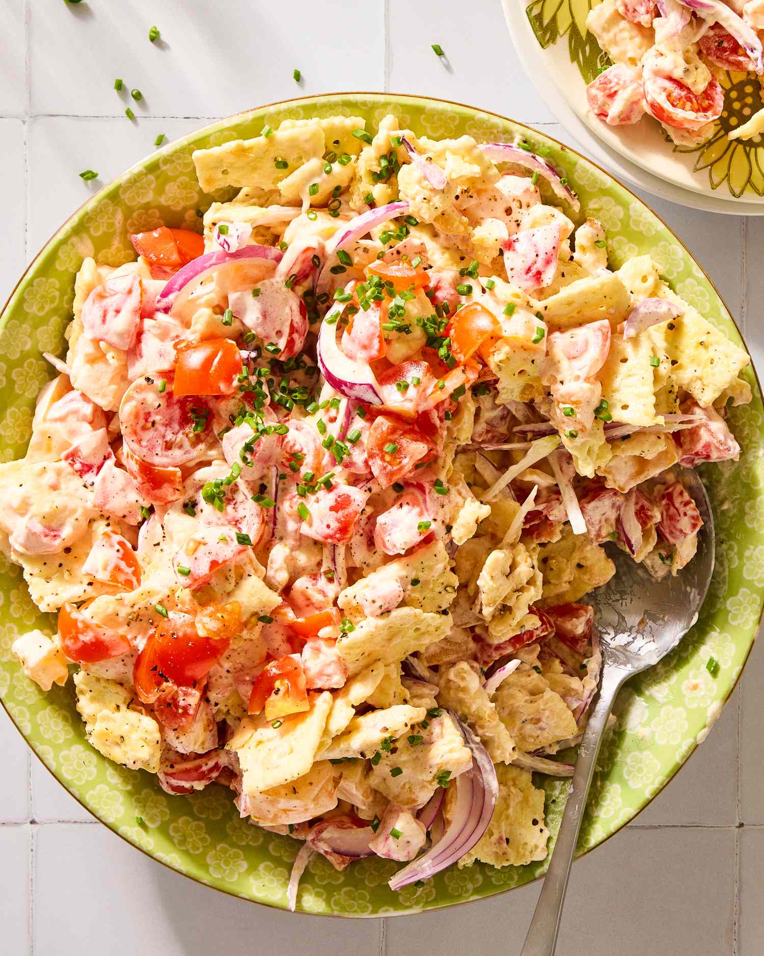 Bowl of tomato cracker salad with a serving spoon