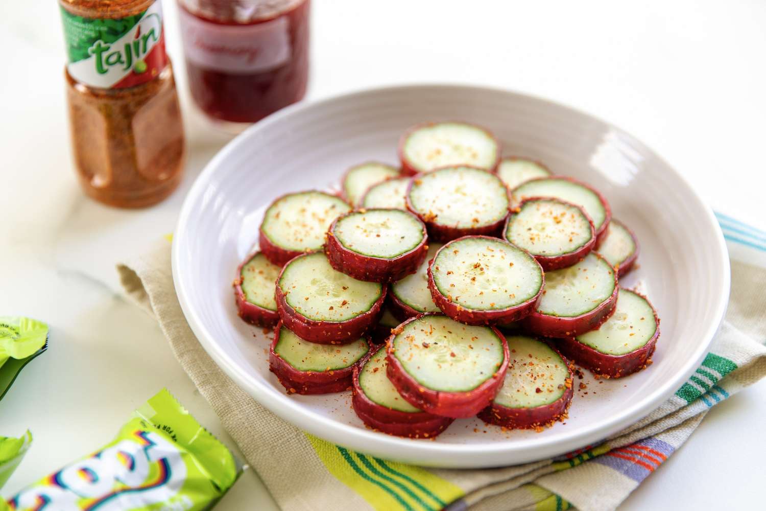 Sliced cucumbers with seasoning on a plate Tajn container in background