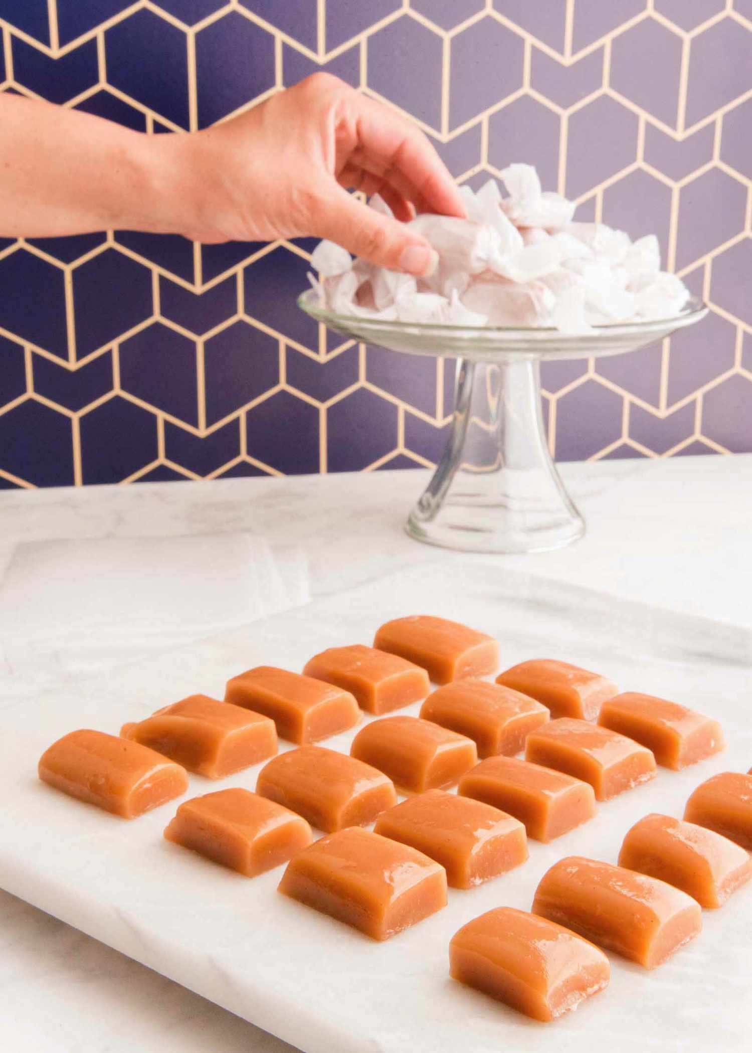 homemade caramel candies on a plate and more wrapped on a pedestal