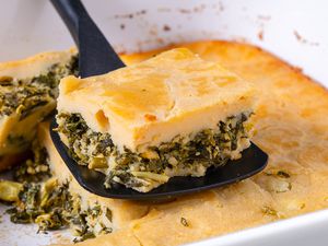 slice of bastaria on a spatula with more in the casserole dish under the spatula